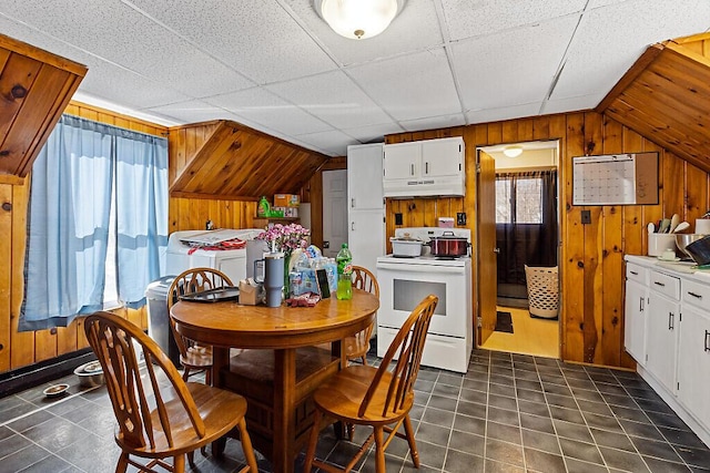 dining room featuring dark tile patterned floors, washer / clothes dryer, and wood walls