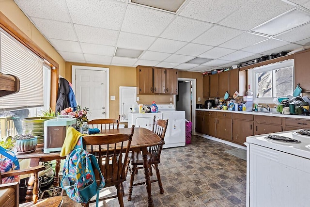 kitchen with brown cabinetry, light countertops, white electric range, a paneled ceiling, and a sink