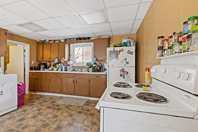 kitchen featuring washer / clothes dryer, white appliances, light countertops, and brown cabinetry