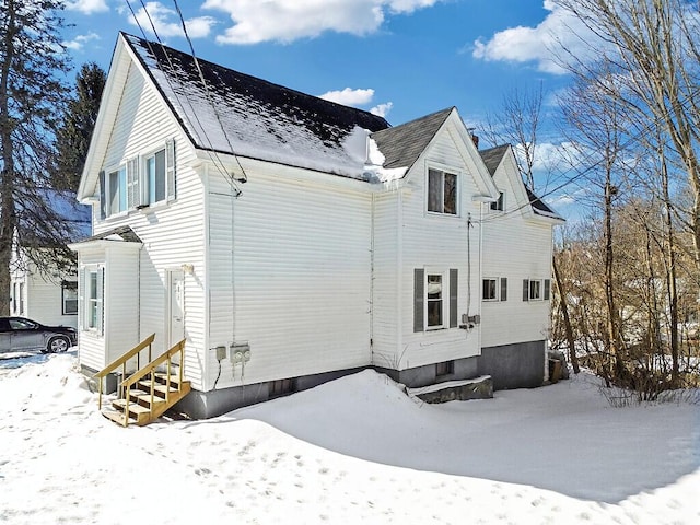 snow covered rear of property featuring entry steps