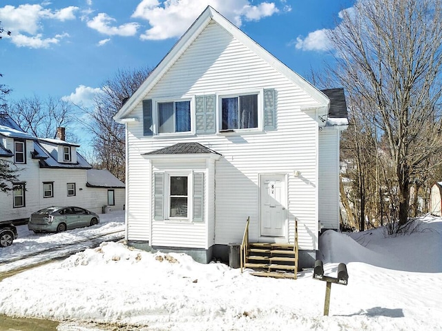 snow covered back of property featuring a garage