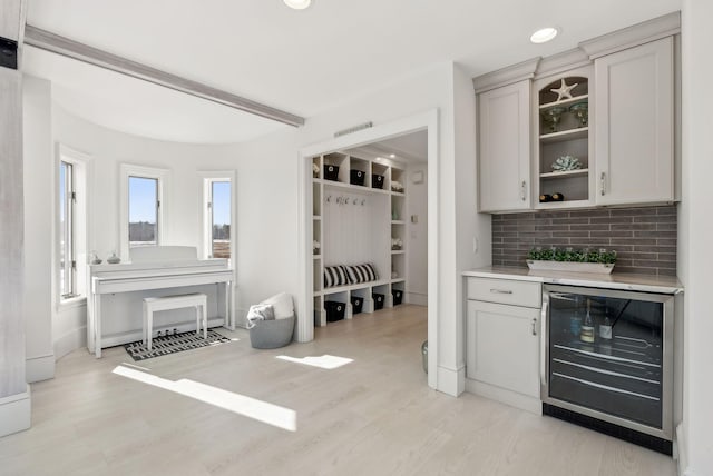 bar featuring wine cooler, backsplash, light wood-style flooring, and recessed lighting