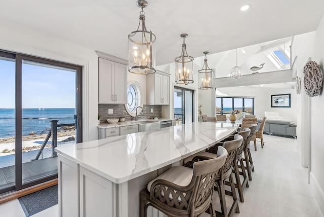 kitchen with a spacious island, backsplash, open floor plan, a sink, and a kitchen bar