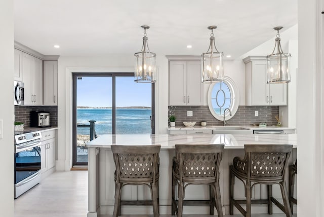 kitchen featuring appliances with stainless steel finishes, a sink, a kitchen breakfast bar, and light stone countertops