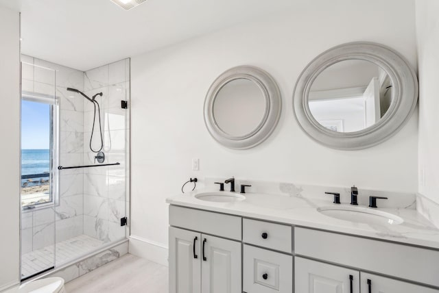 full bath featuring a sink, a marble finish shower, and double vanity