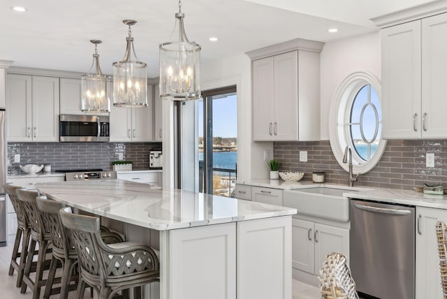 kitchen featuring light stone counters, appliances with stainless steel finishes, a wealth of natural light, and a center island