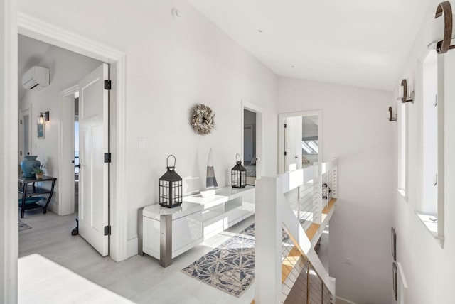 hallway featuring a wall mounted air conditioner, vaulted ceiling, and light wood-style flooring