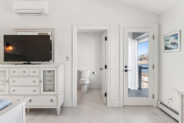 bathroom featuring lofted ceiling, a wall unit AC, toilet, a baseboard heating unit, and wood finished floors