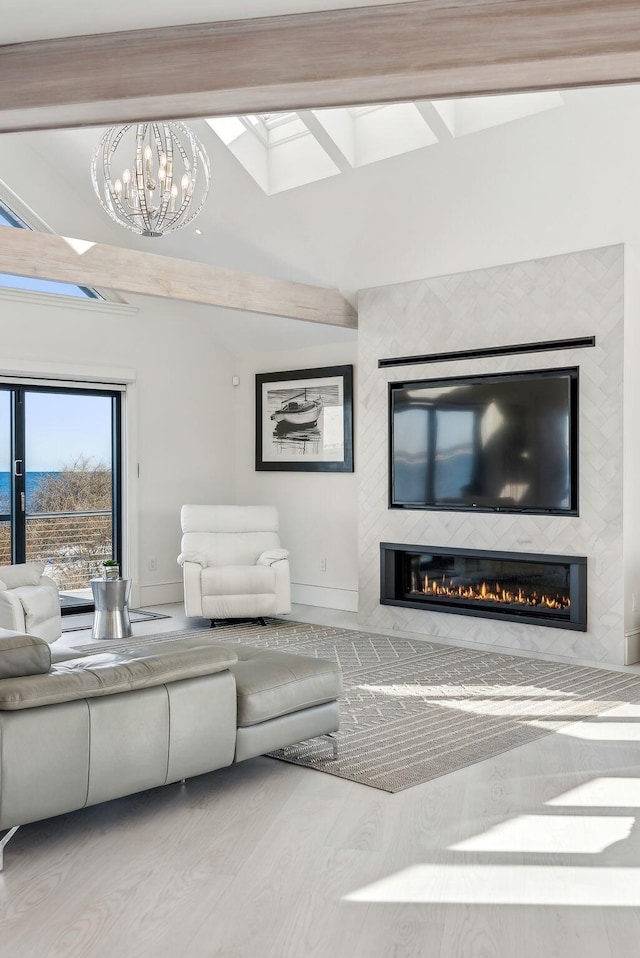 living room with a glass covered fireplace, wood finished floors, vaulted ceiling, and an inviting chandelier