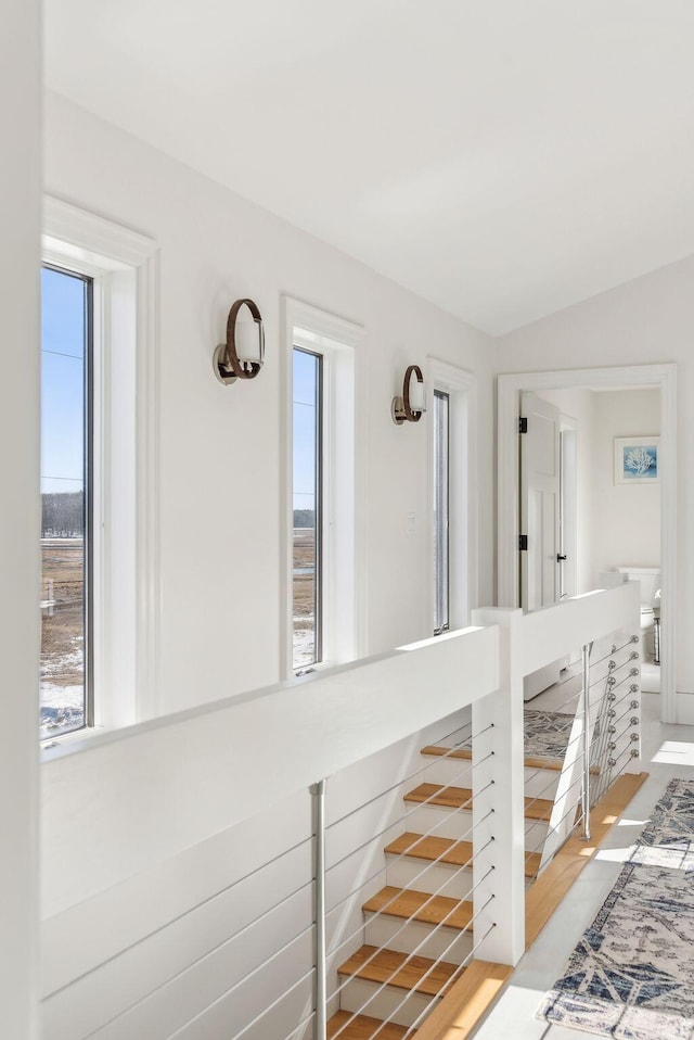 corridor with vaulted ceiling and an upstairs landing