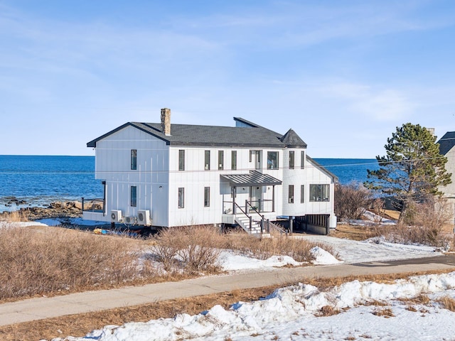 rear view of house featuring a shingled roof, a standing seam roof, a water view, and metal roof