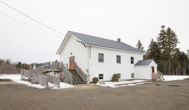 rear view of house with a deck, stairs, a chimney, and metal roof