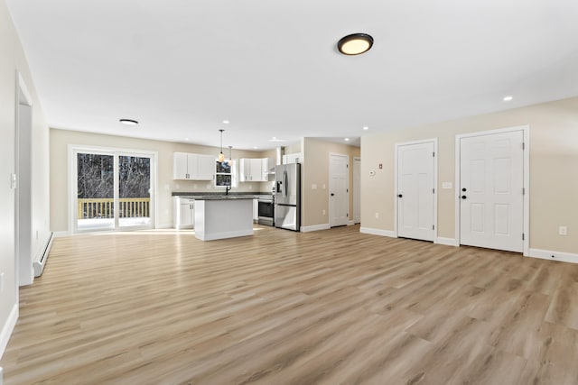 unfurnished living room with a baseboard heating unit, recessed lighting, light wood-type flooring, and baseboards