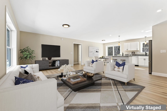 living room with recessed lighting, light wood-type flooring, and baseboards