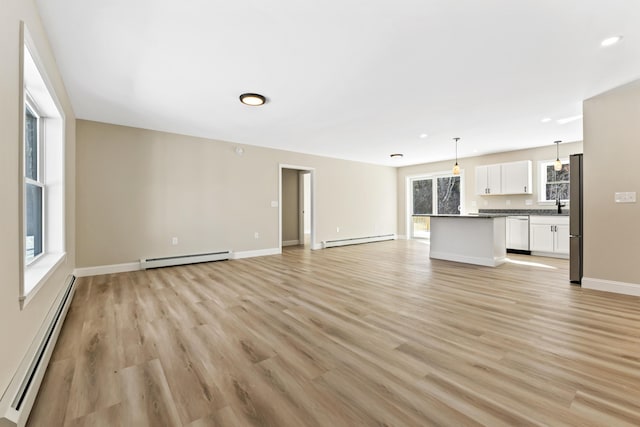 unfurnished living room featuring a baseboard heating unit, a baseboard radiator, and light wood-style floors