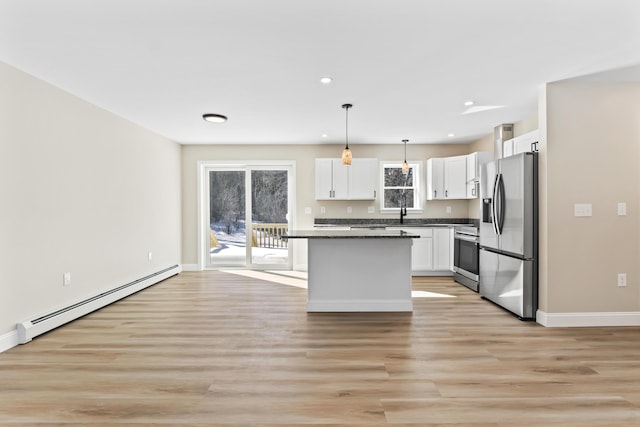 kitchen featuring dark countertops, stove, a baseboard heating unit, white cabinets, and stainless steel fridge with ice dispenser