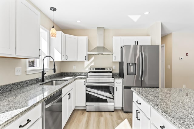 kitchen featuring stainless steel appliances, white cabinets, a sink, and wall chimney exhaust hood