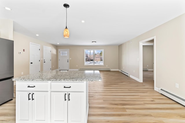 kitchen with a baseboard heating unit, baseboard heating, freestanding refrigerator, and white cabinets