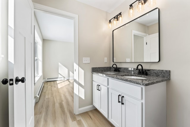 full bath featuring a baseboard heating unit, a sink, and wood finished floors