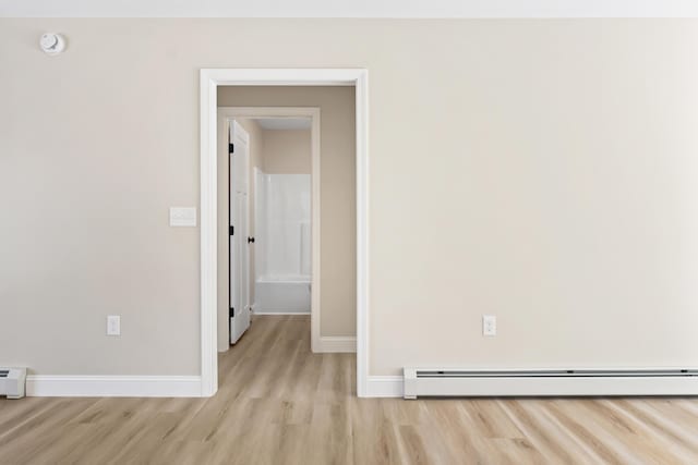 unfurnished room featuring a baseboard radiator, light wood-style flooring, a baseboard heating unit, and baseboards