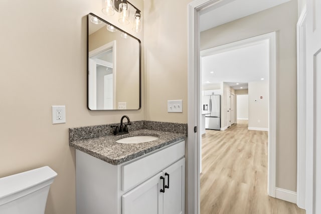 bathroom featuring vanity, wood finished floors, toilet, and baseboards