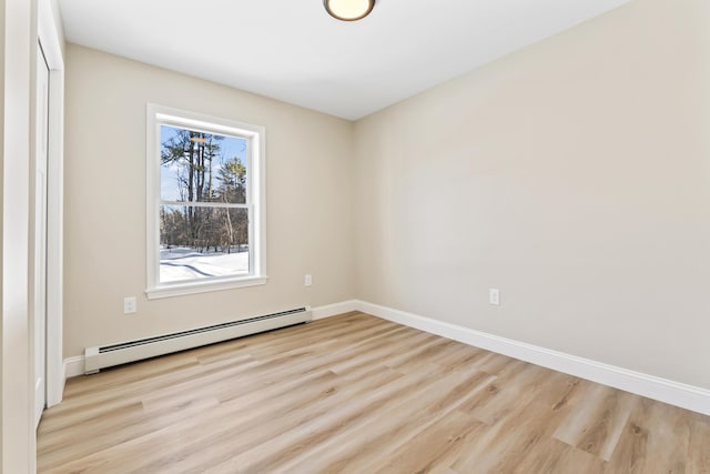 spare room with baseboards, baseboard heating, and wood finished floors