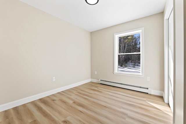 empty room featuring a baseboard heating unit, light wood-style floors, and baseboards