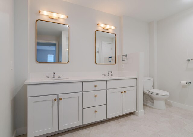 full bath featuring toilet, double vanity, baseboards, and a sink