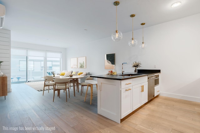 kitchen featuring light wood-style floors, dark countertops, white cabinets, and a sink