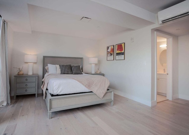 bedroom featuring baseboards, visible vents, light wood finished floors, and a wall mounted AC