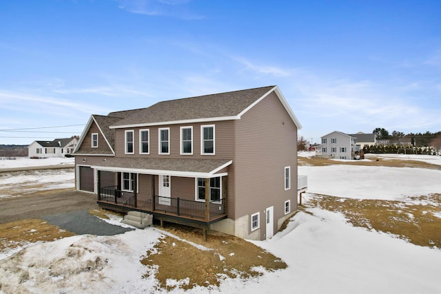 view of front of house with a deck, aphalt driveway, a garage, and a shingled roof