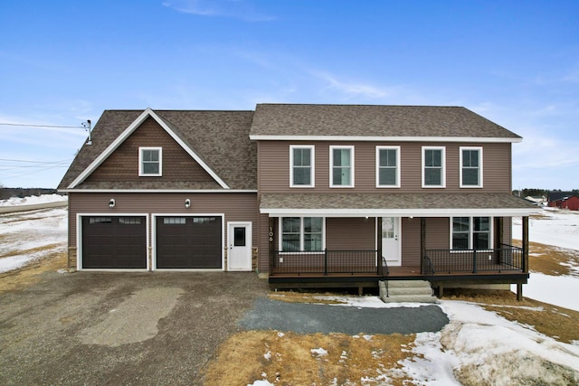 view of front facade with a porch, a garage, driveway, and roof with shingles