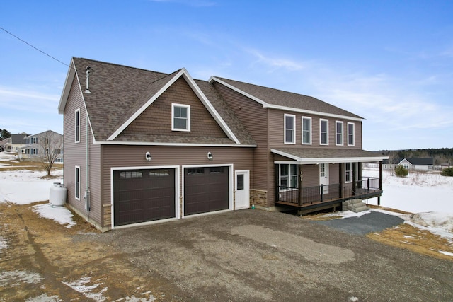 view of front of property featuring covered porch, driveway, and a shingled roof