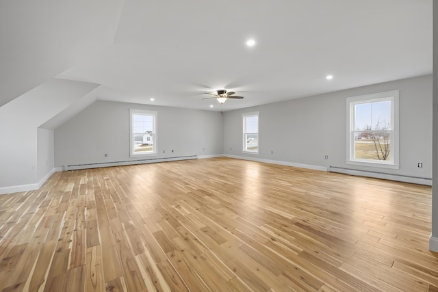 unfurnished living room featuring a baseboard radiator, plenty of natural light, and light wood finished floors