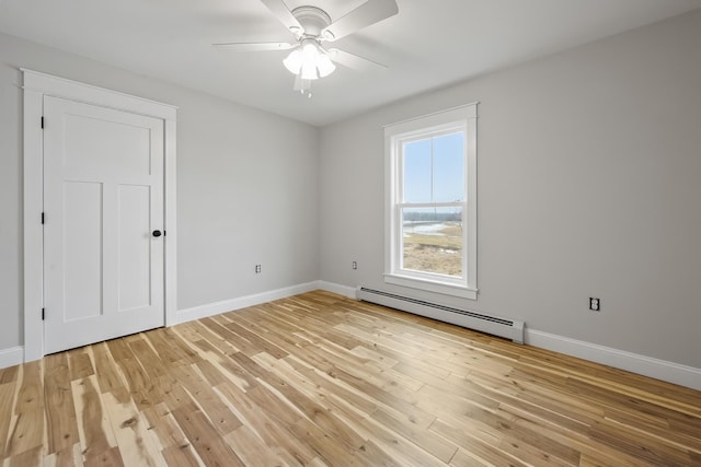 spare room featuring light wood finished floors, a ceiling fan, baseboards, and a baseboard radiator