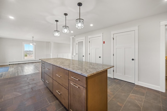 kitchen featuring decorative light fixtures, light stone counters, a kitchen island, a baseboard radiator, and baseboards