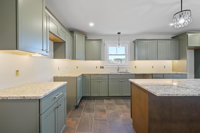 kitchen featuring light stone countertops, recessed lighting, a sink, hanging light fixtures, and decorative backsplash