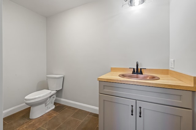 bathroom featuring vanity, toilet, and baseboards