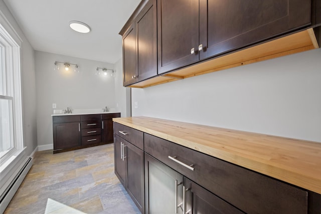 bar featuring a sink, stone finish flooring, baseboards, and baseboard heating