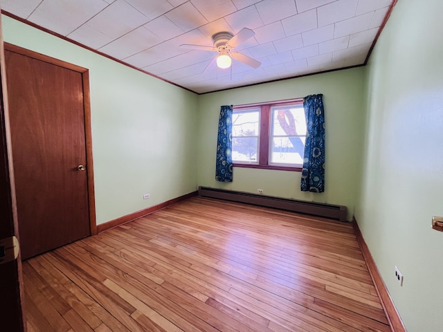 interior space with light wood-style flooring, a baseboard heating unit, ornamental molding, a ceiling fan, and baseboards