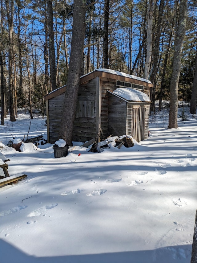 snow covered structure featuring an outbuilding and a shed