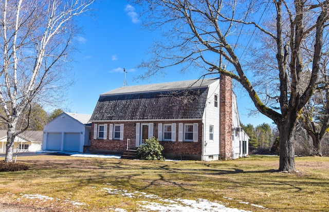colonial inspired home with a front yard, brick siding, a garage, a gambrel roof, and a shingled roof