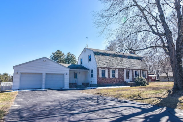 dutch colonial with a garage, aphalt driveway, a chimney, brick siding, and a gambrel roof
