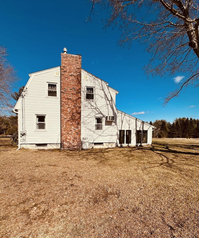 back of property with a yard, a gambrel roof, and a chimney