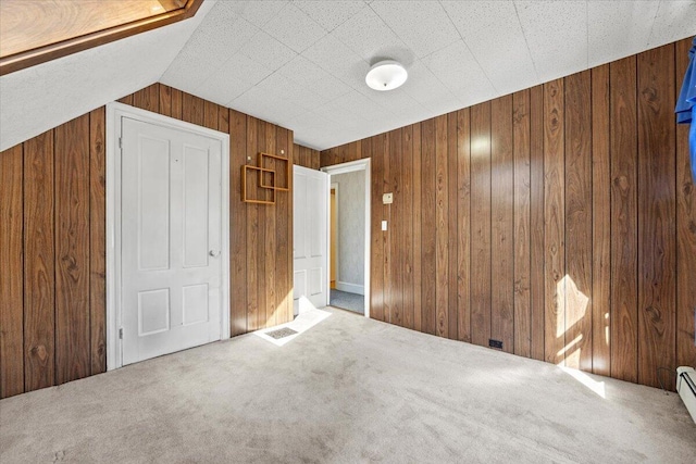 interior space with carpet floors, visible vents, wooden walls, and a baseboard heating unit