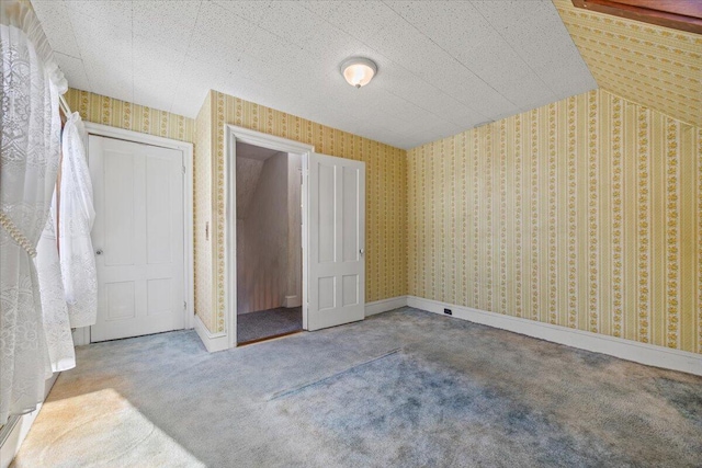 unfurnished bedroom with baseboards, a closet, carpet flooring, and wallpapered walls