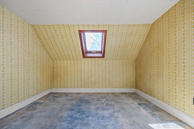 additional living space with carpet floors, baseboards, lofted ceiling with skylight, and wallpapered walls