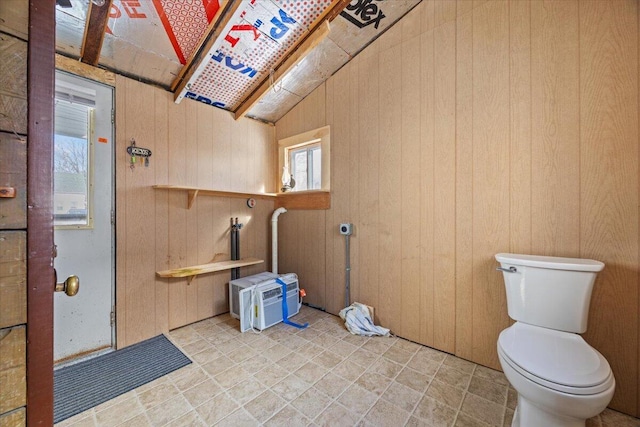 bathroom featuring lofted ceiling, wood walls, and toilet