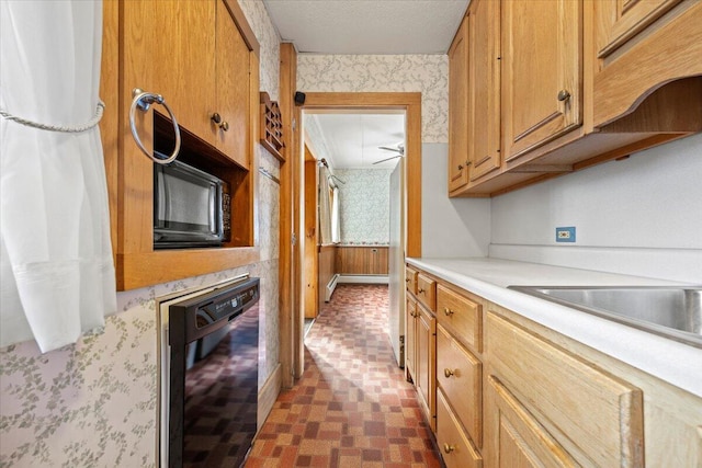 kitchen with wallpapered walls, light countertops, a textured ceiling, black appliances, and a sink