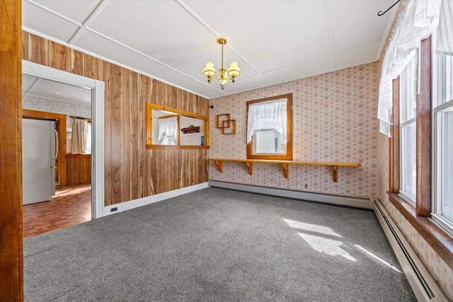 empty room with a baseboard radiator, carpet flooring, and a notable chandelier